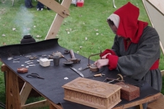 Enkele tinnen munten, mallen en een vertindmachine aan het werk