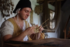 The basket maker at work.  In progress: loose end filling of a round white wicker bottom