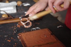 Cleaning a pewter belt buckle that has just been cast in a Delft sand mold